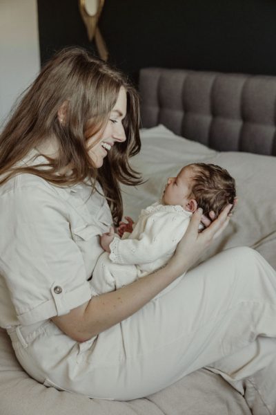 Mama met baby in haar armen lachend tijdens een newbornshoot